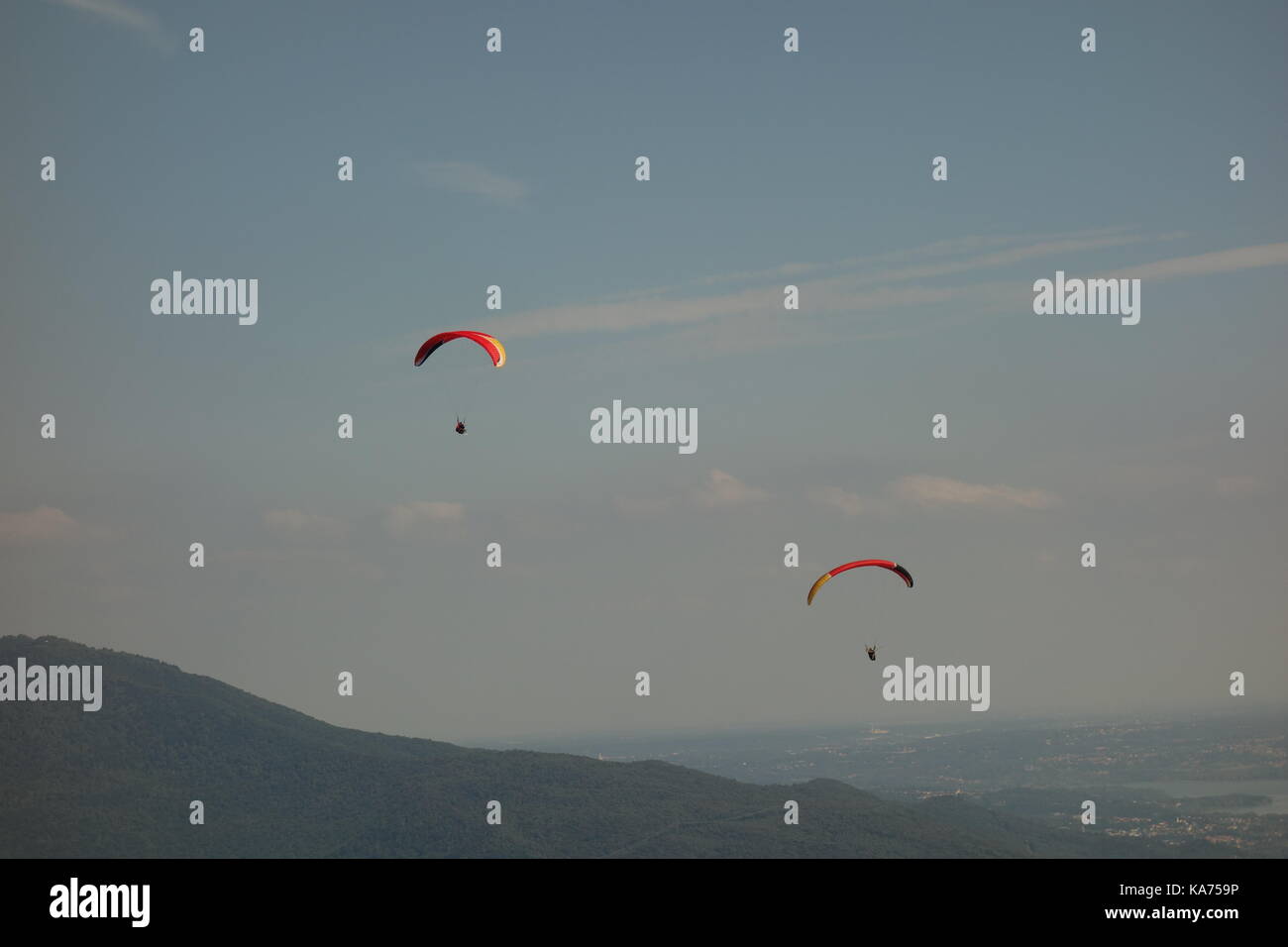 Adrenalin sport. Paragliding men in the blue sky of Laveno Mombello, Italy Stock Photo