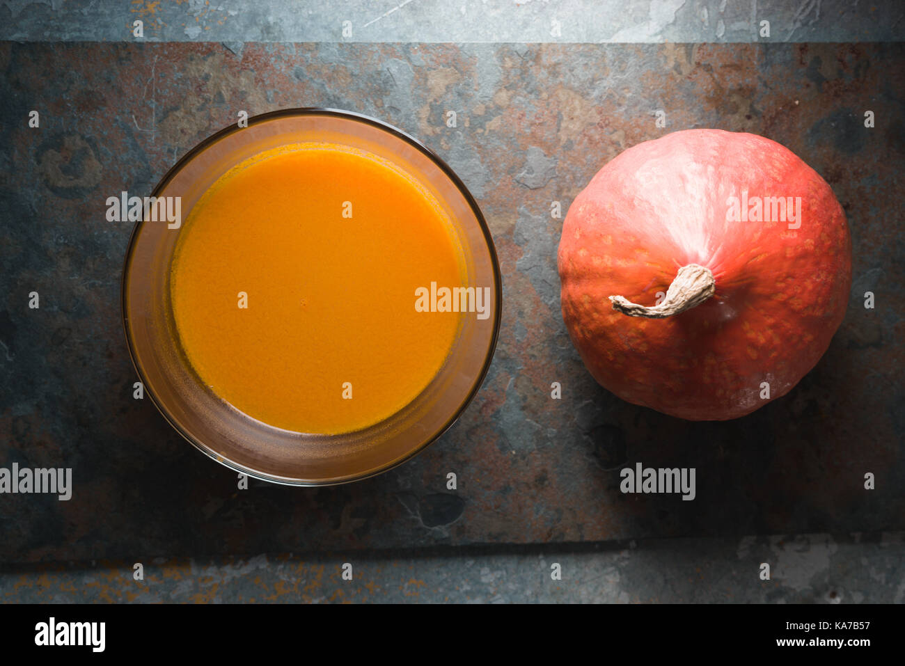 Pumpkin soup and orange pumpkin on gray slate horizontal Stock Photo