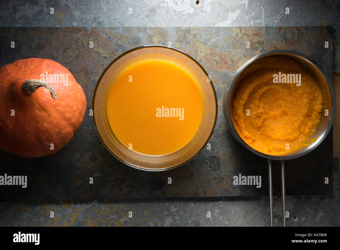 Pumpkin puree in a saucepan, pumpkin soup and pumpkin on a gray stone horizontal Stock Photo