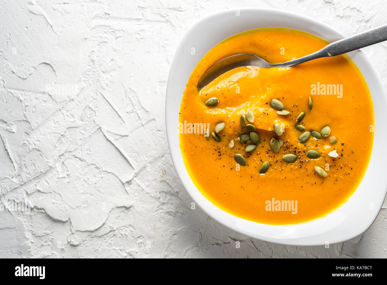 Pumpkin soup with seeds and a spoon in a plate horizontal Stock Photo