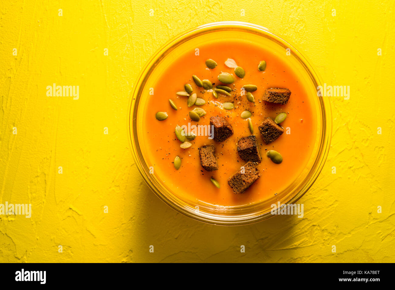 Pumpkin soup with seeds and croutons on a yellow table horizontal Stock Photo