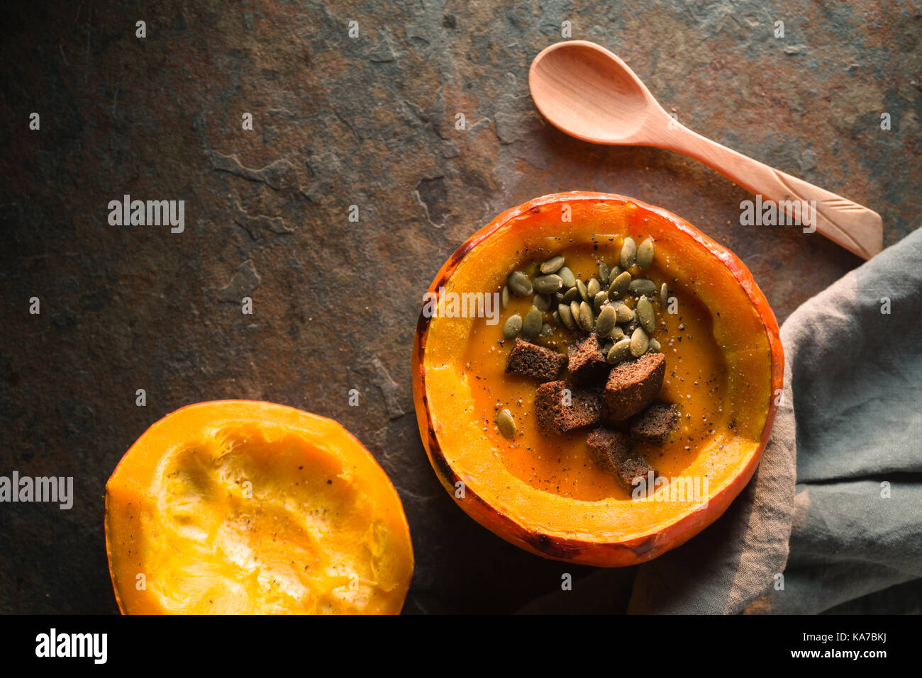 Pumpkin soup with seeds and croutons in pumpkin, napkin and spoon horizontal Stock Photo