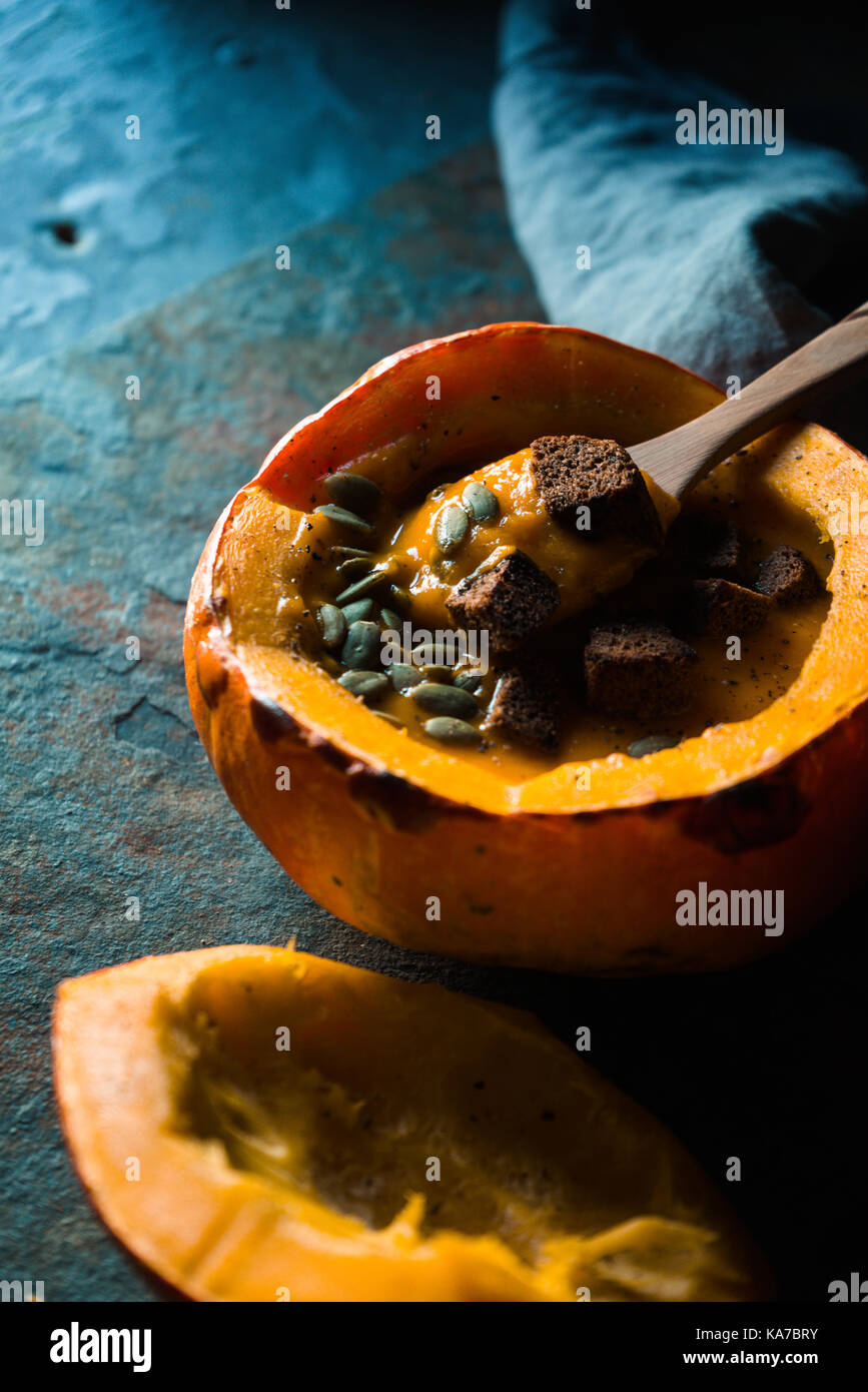 Spoon in pumpkin soup and pumpkin with sunflower seeds and croutons vertical Stock Photo