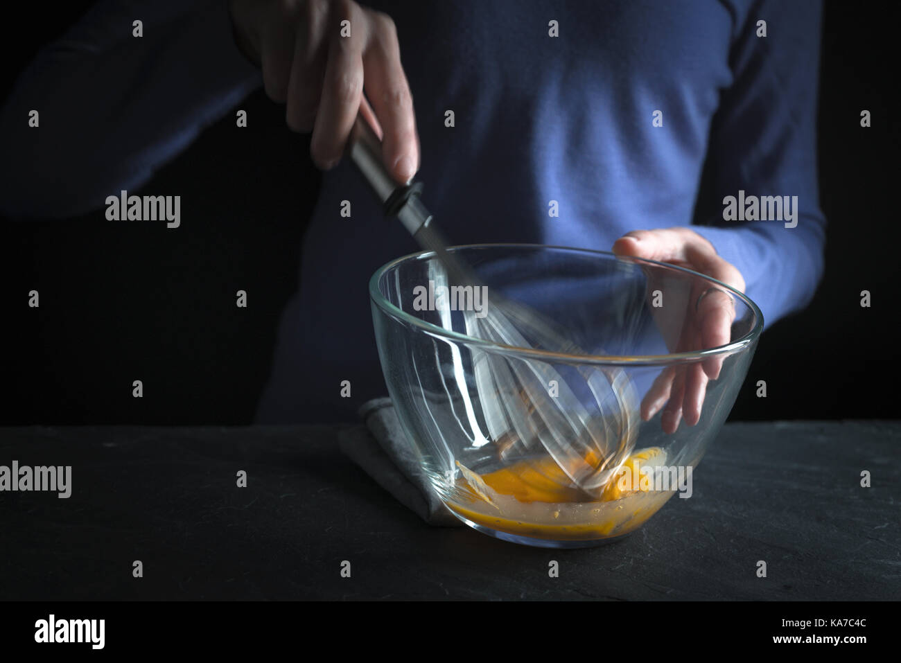 Beat yolks in a glass bowl with a whisk on a purple background horizontal Stock Photo