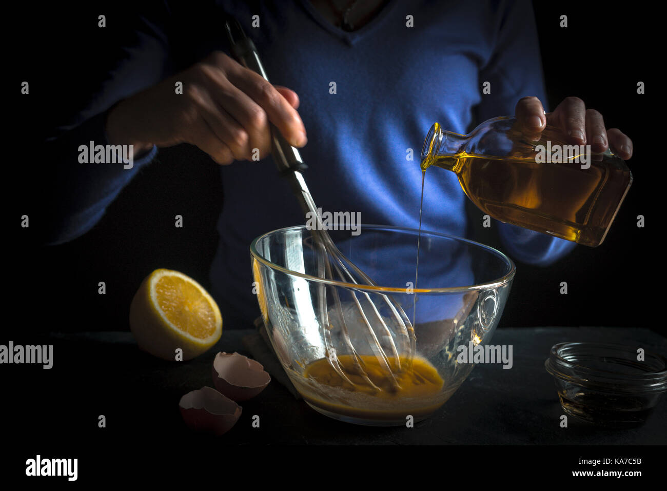 Olive oil is poured into whipped yolks for the preparation of mayonnaise horizontal Stock Photo
