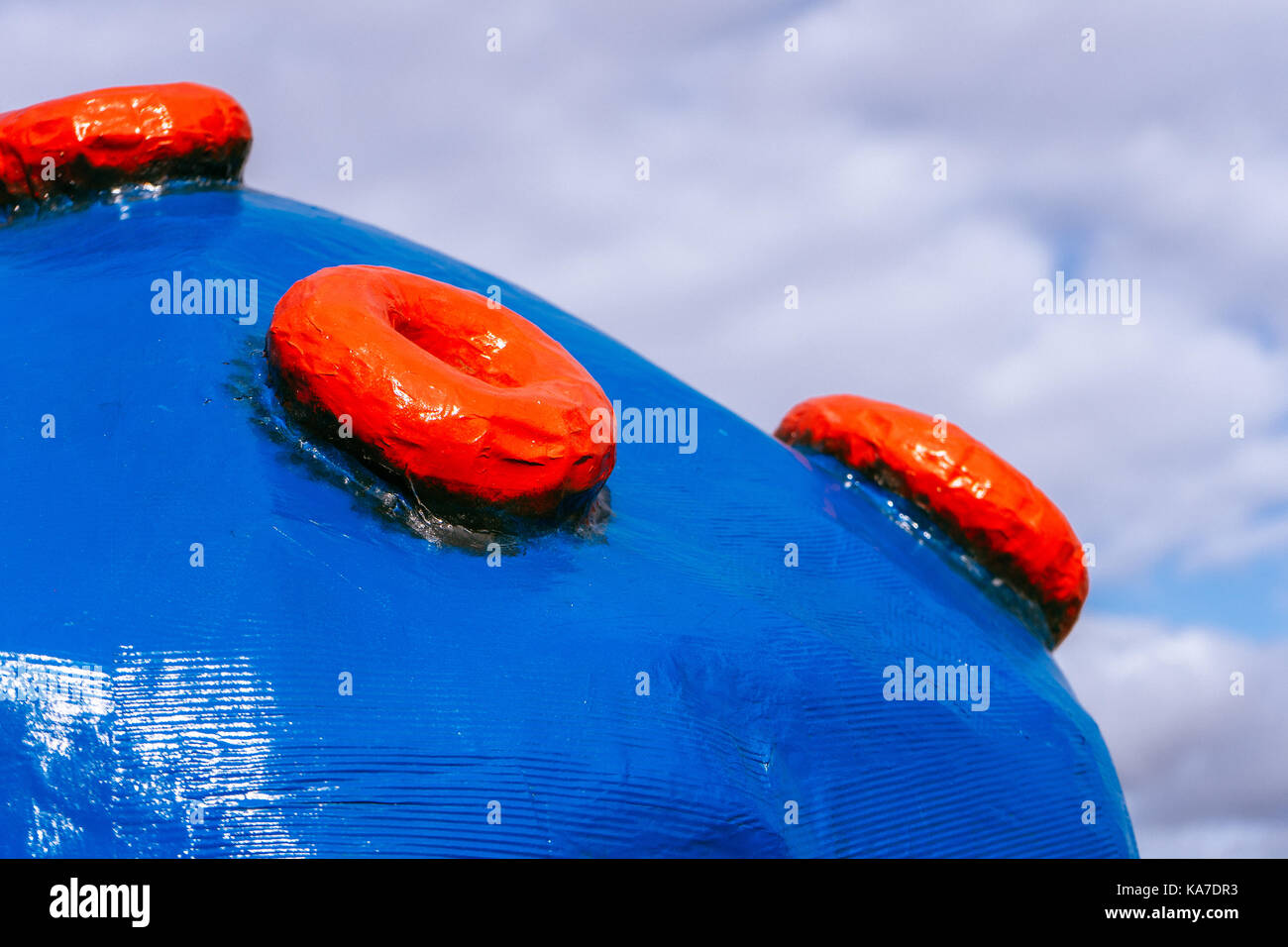 Large blue plastic ball with red buttons on the background of clouds horizontal Stock Photo