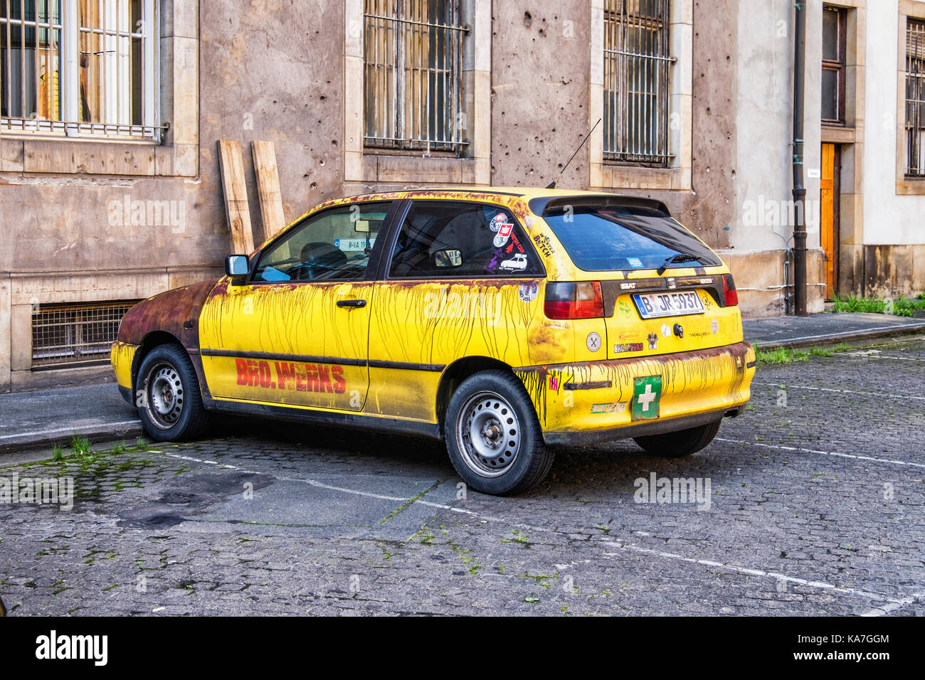 Berlin Mitte. Battered, rusty yellow SEAT IBiza car parked next to old war damaged Molkenmarkt building. Old Bro.werks vehicle Stock Photo