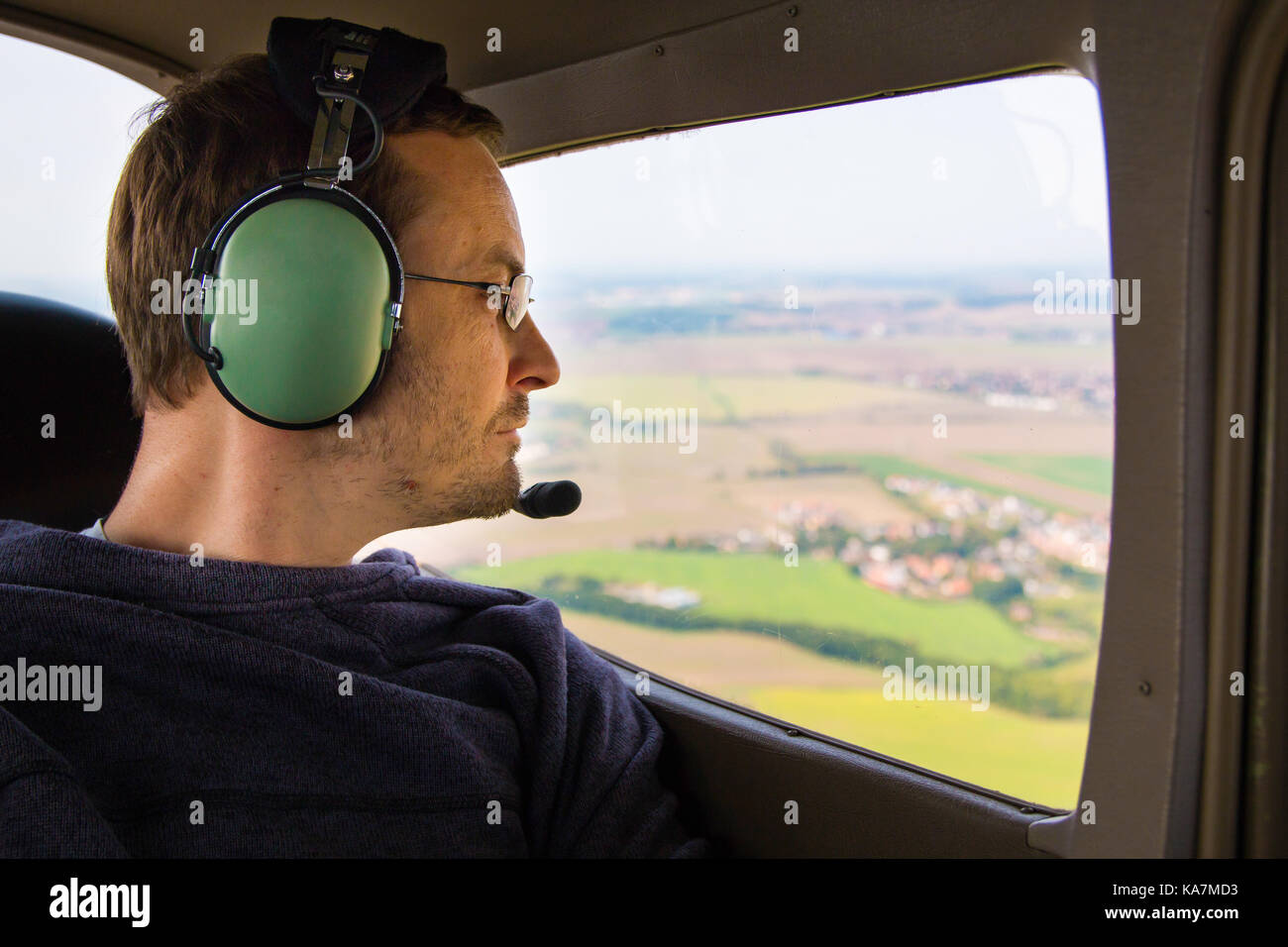 Portrait of young adult passenger sitting in private air plane and looking out window Stock Photo