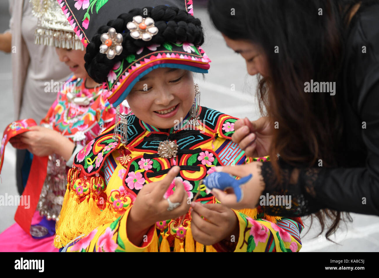 Beijing, China. 25th Sep, 2017. Shen Yanyan (C), an inheritor of embroidery which is an intangible cultural heritage of the Qiang ethnic group, teaches a tourist to make sachet in Beijing, capital of China, Sept. 25, 2017. The 4th Badachu park cultural festival will be held from Oct. 1 to Oct. 7 in Badachu Park in Beijing. Inheritors of intangible cultural heritages from 17 ethnic minorities will present cultural heritages to enrich tourists' National Day holiday. Credit: Li Jundong/Xinhua/Alamy Live News Stock Photo