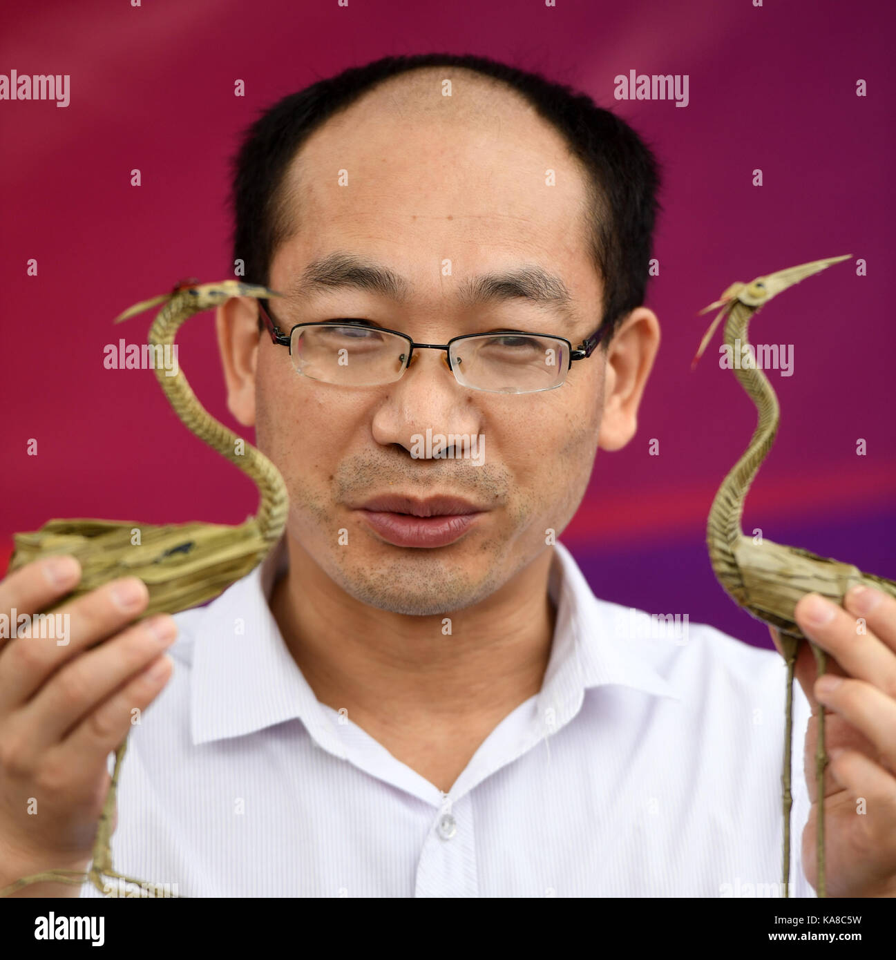 Beijing, China. 25th Sep, 2017. Huang Qiang, an inheritor of straw weaving intangible cultural heritage of the Qiang ethnic group, shows straw-weaved cranes in Beijing, capital of China, Sept. 25, 2017. The 4th Badachu park cultural festival will be held from Oct. 1 to Oct. 7 in Badachu Park in Beijing. Inheritors of intangible cultural heritages from 17 ethnic minorities will present cultural heritages to enrich tourists' National Day holiday. Credit: Li Jundong/Xinhua/Alamy Live News Stock Photo