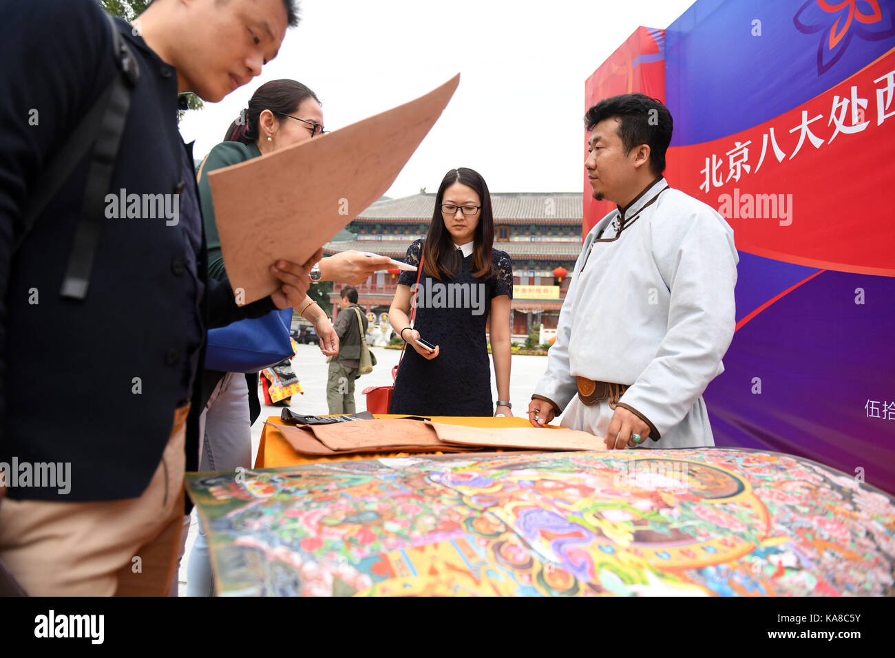 Beijing, China. 25th Sep, 2017. An inheritor (1st R) of leather carved picture, an intangible cultural heritage of Mongolian ethnic group, introduces leather carved pictures to tourists in Beijing, capital of China, Sept. 25, 2017. The 4th Badachu park cultural festival will be held from Oct. 1 to Oct. 7 in Badachu Park in Beijing. Inheritors of intangible cultural heritages from 17 ethnic minorities will present cultural heritages to enrich tourists' National Day holiday. Credit: Li Jundong/Xinhua/Alamy Live News Stock Photo