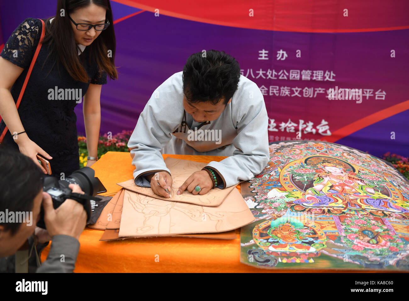 Beijing, China. 25th Sep, 2017. An inheritor (R) of leather carved picture, an intangible cultural heritage of Mongolian ethnic group, makes leather carved pictures in Beijing, capital of China, Sept. 25, 2017. The 4th Badachu park cultural festival will be held from Oct. 1 to Oct. 7 in Badachu Park in Beijing. Inheritors of intangible cultural heritages from 17 ethnic minorities will present cultural heritages to enrich tourists' National Day holiday. Credit: Li Jundong/Xinhua/Alamy Live News Stock Photo