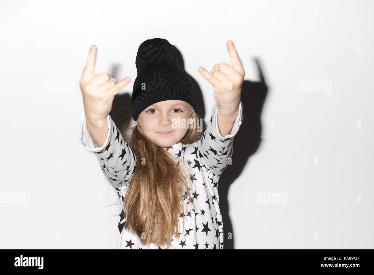 Cute girl gesturing rock at camera on a white background Stock Photo