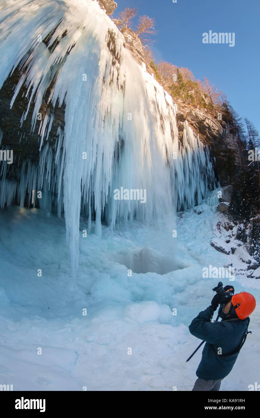 Photographer taking photos of frozen Pericnik waterfall in Vrata valley, Julian alps. Stock Photo