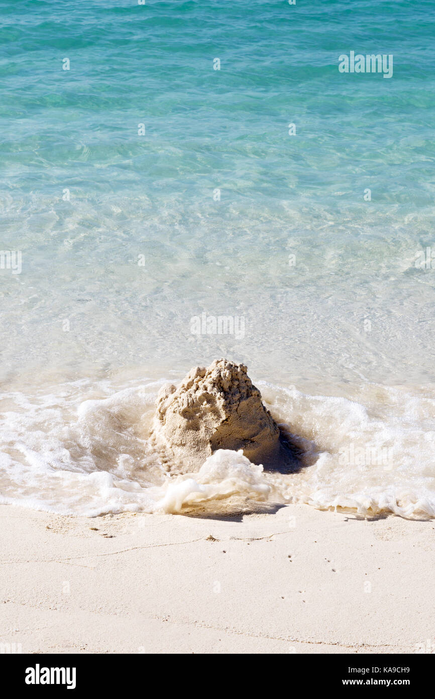 Sandcastle on the beach being washed away by the waves - concept of inevitability, time, temporary, - the Maldives, Asia Stock Photo