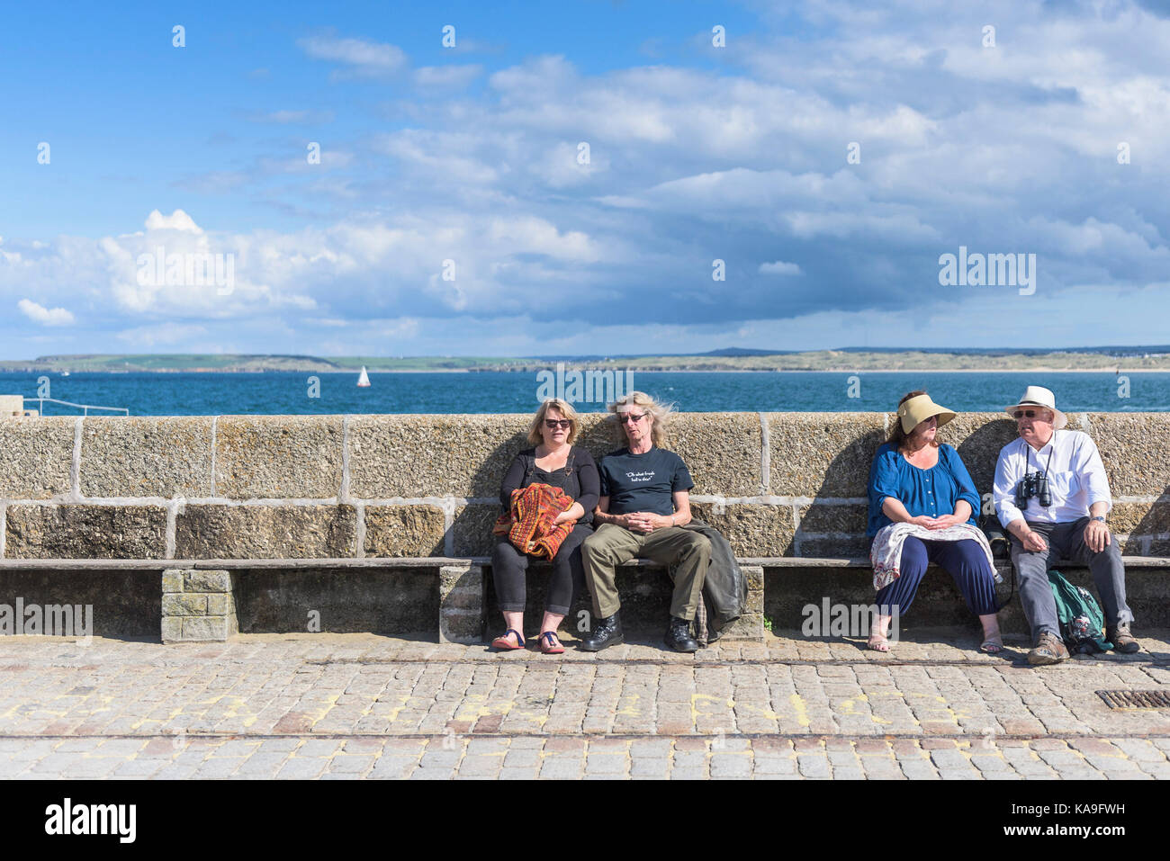 St Ives - holidaymakers sitting and relaxing on Smeatons Pier in St Ives in Cornwall. Stock Photo