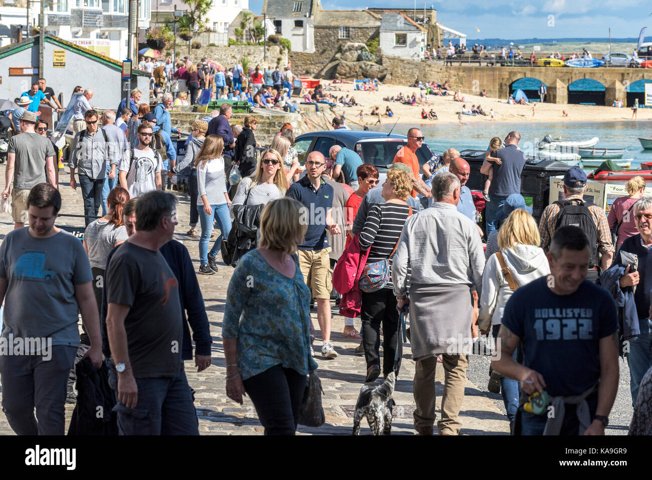 St Ives - holidaymakers relaxing and strolling around St Ives Harbour Beach in Cornwall. Stock Photo