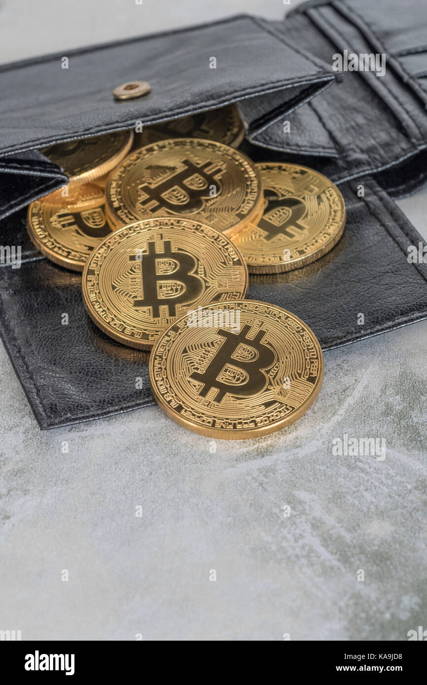 Gold Bitcoins spilling from black billfold wallet. For Bitcoin wallet, virtual money, cryptocurrency, peer to peer transactions, Bitcoin price crash. Stock Photo