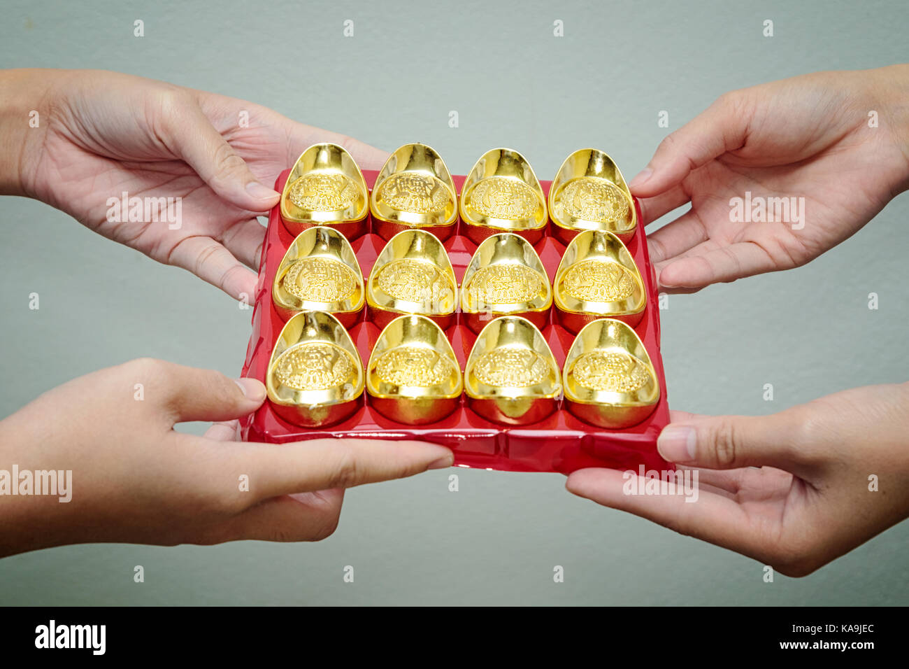 Hand giving gold ingot to someone for Chinese New Year celebration Stock Photo