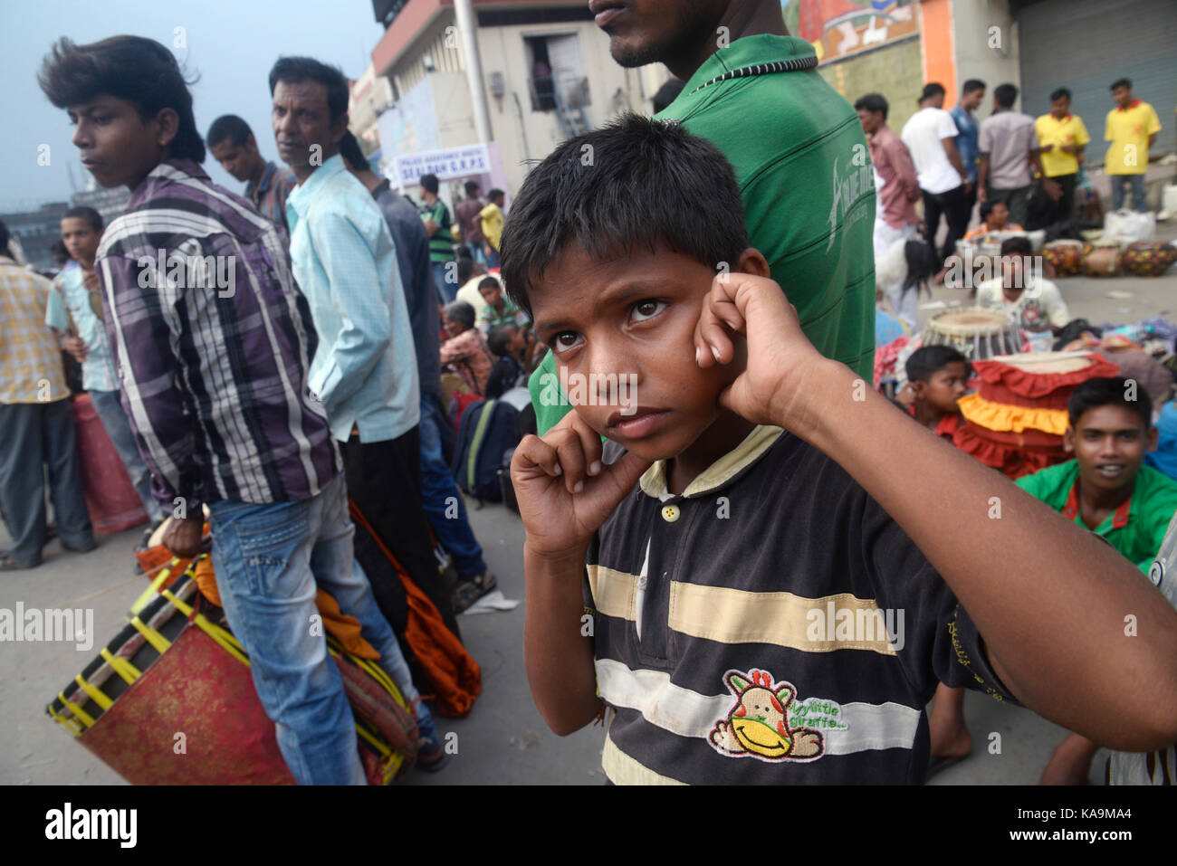 A child block his ear with finger from loud drum beat in Sealdah