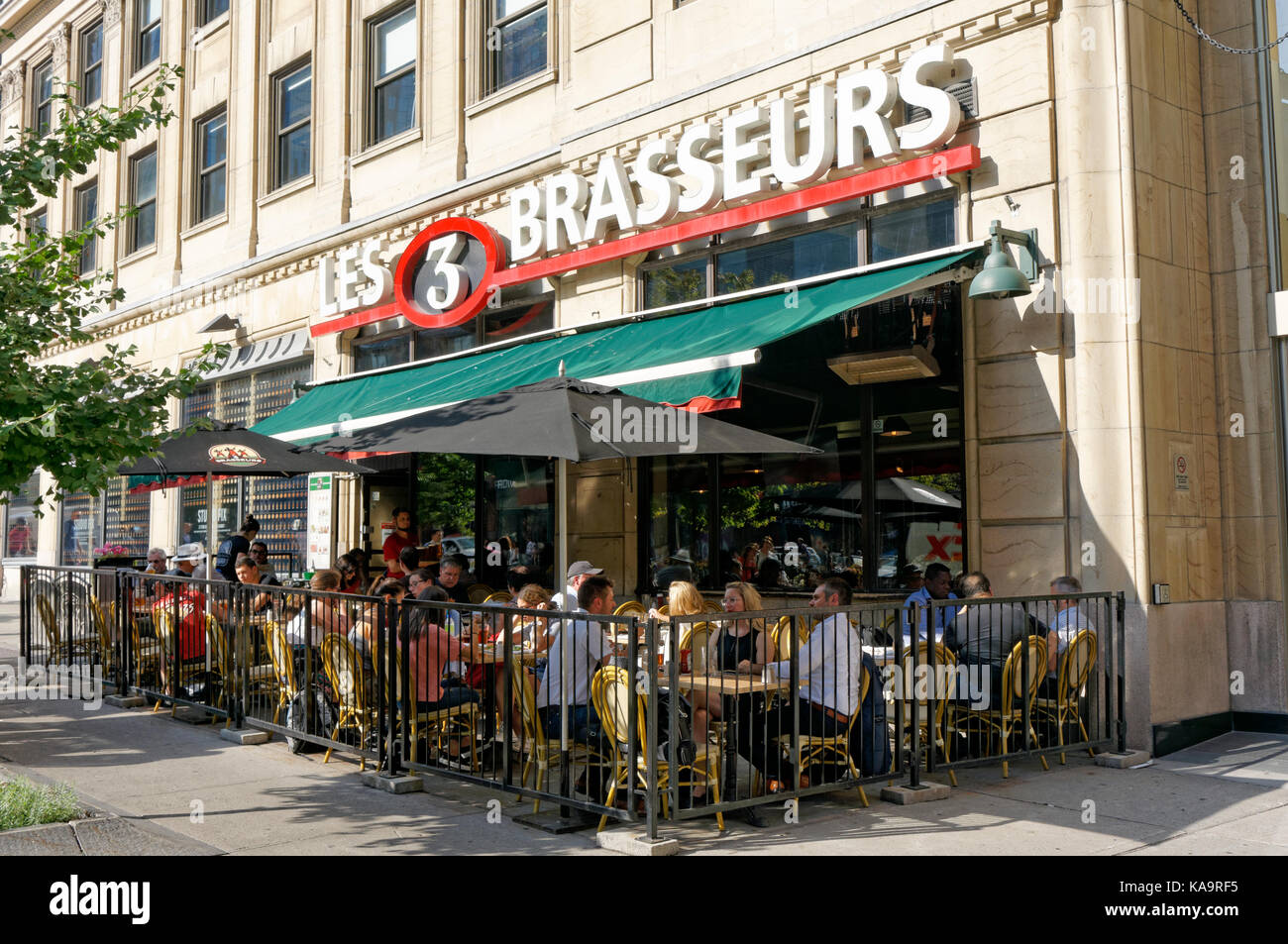 People sitting and talking outdoors at  Les 3  Brasseurs microbrewery restaurant on McGill College Avenue in downtown Montreal, Quebec, Canada Stock Photo