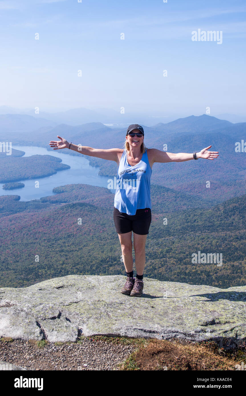 Female hiker standing on the edge of a cliff with her arms out at the ...