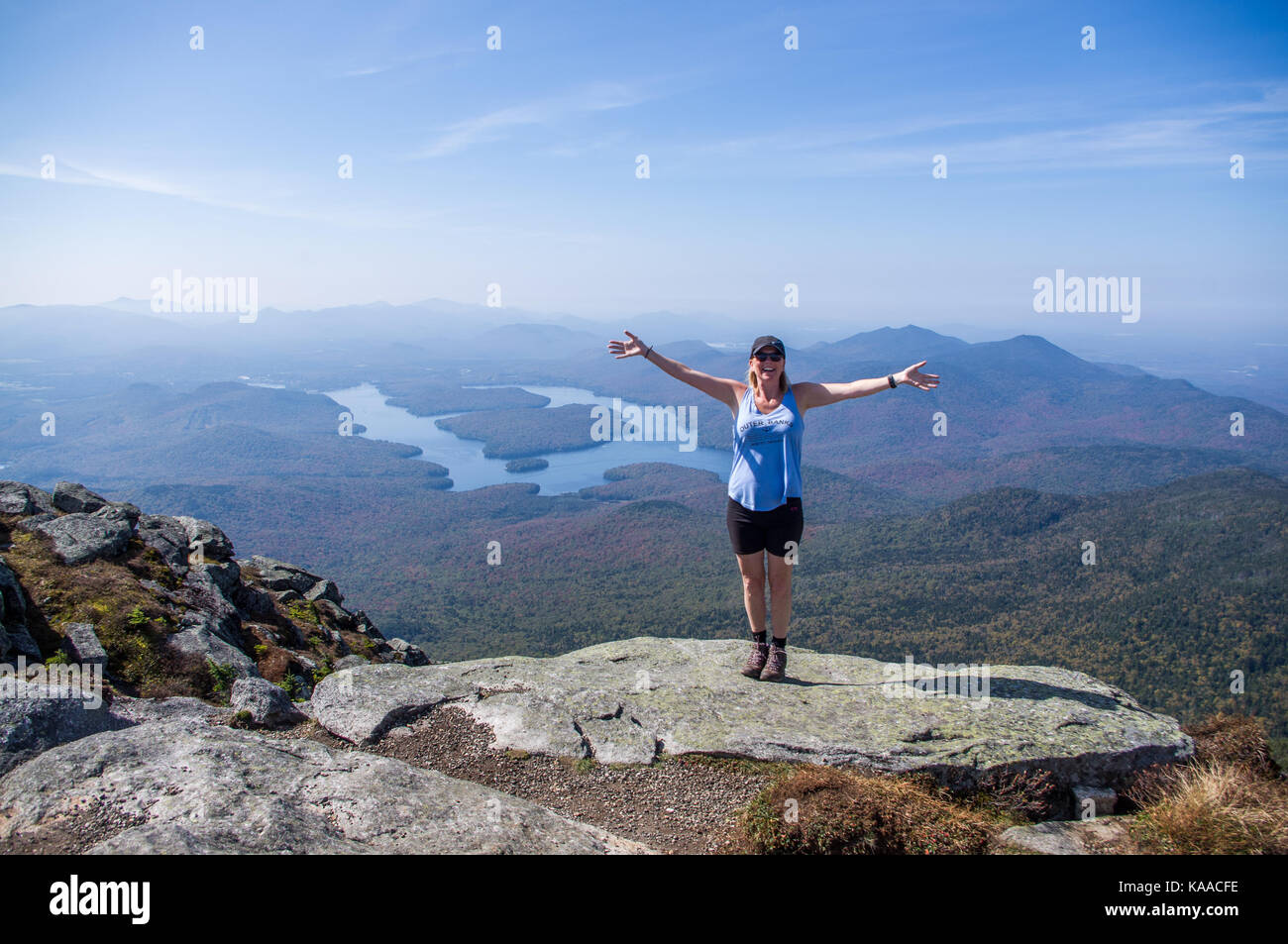 Female hiker standing on the edge of a cliff with her arms out at the ...
