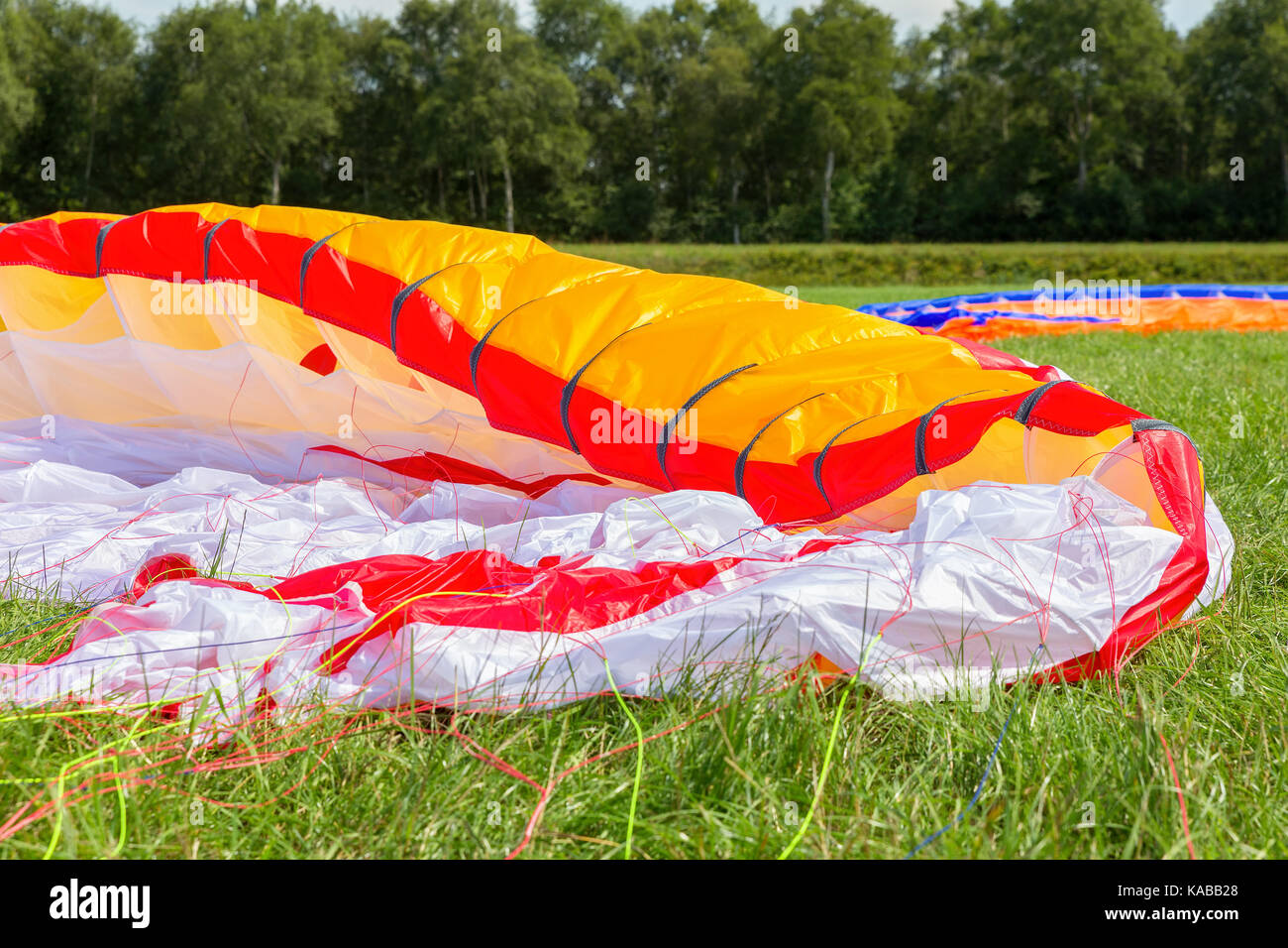 Parachute of paraglider lying in green meadow Stock Photo