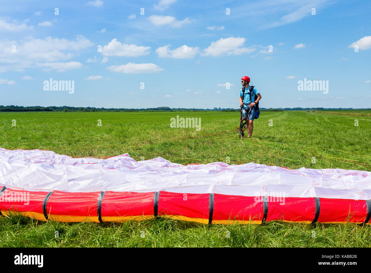 Young male paraglider waiting with parachute in meadow Stock Photo