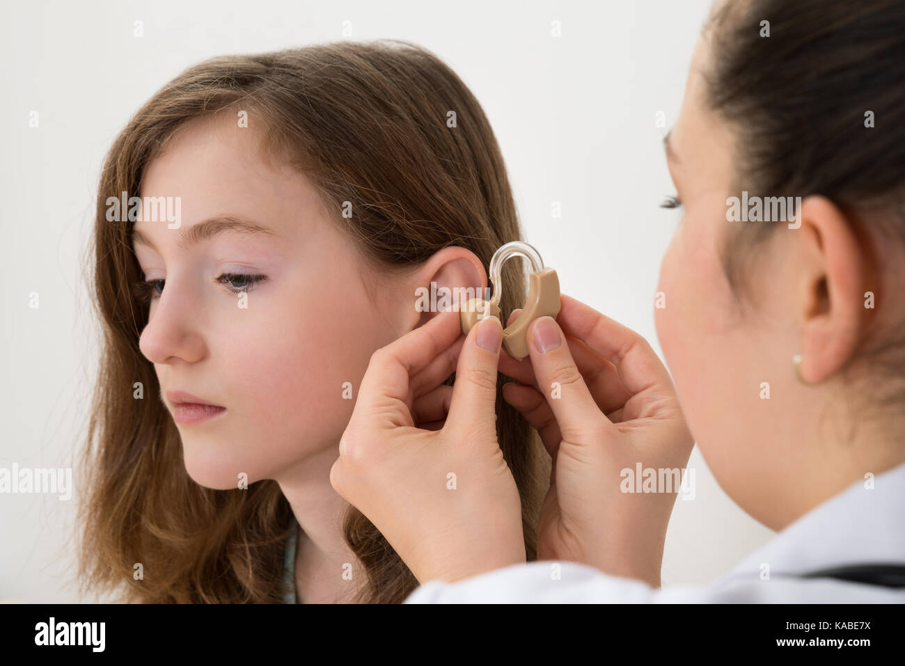 Close-up Of Doctor Inserting Hearing Aid In The Ear Of A Girl Stock Photo
