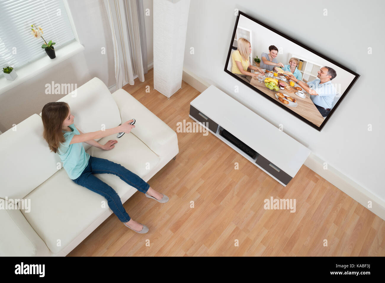 Girl Holding Remote Control In Front Of Television In Living Room Stock Photo