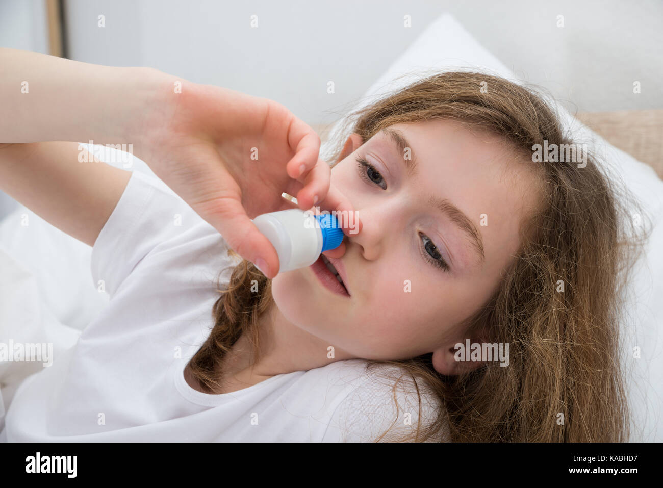 Close-up Of Sick Girl Using Nasal Spray In Bedroom Stock Photo