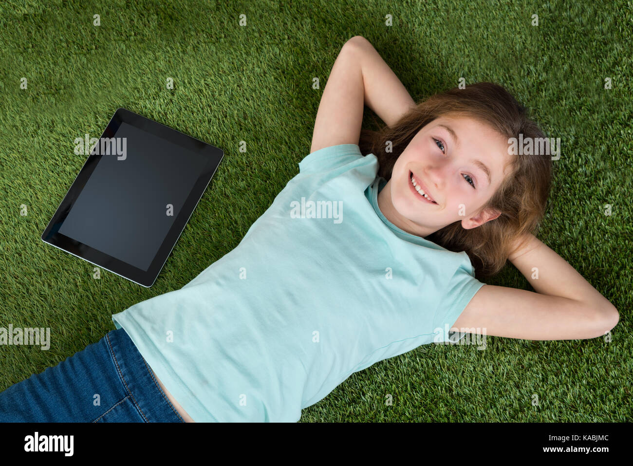 Happy Girl With Digital Tablet And Mobile Phone Lying On Green Lawn ...