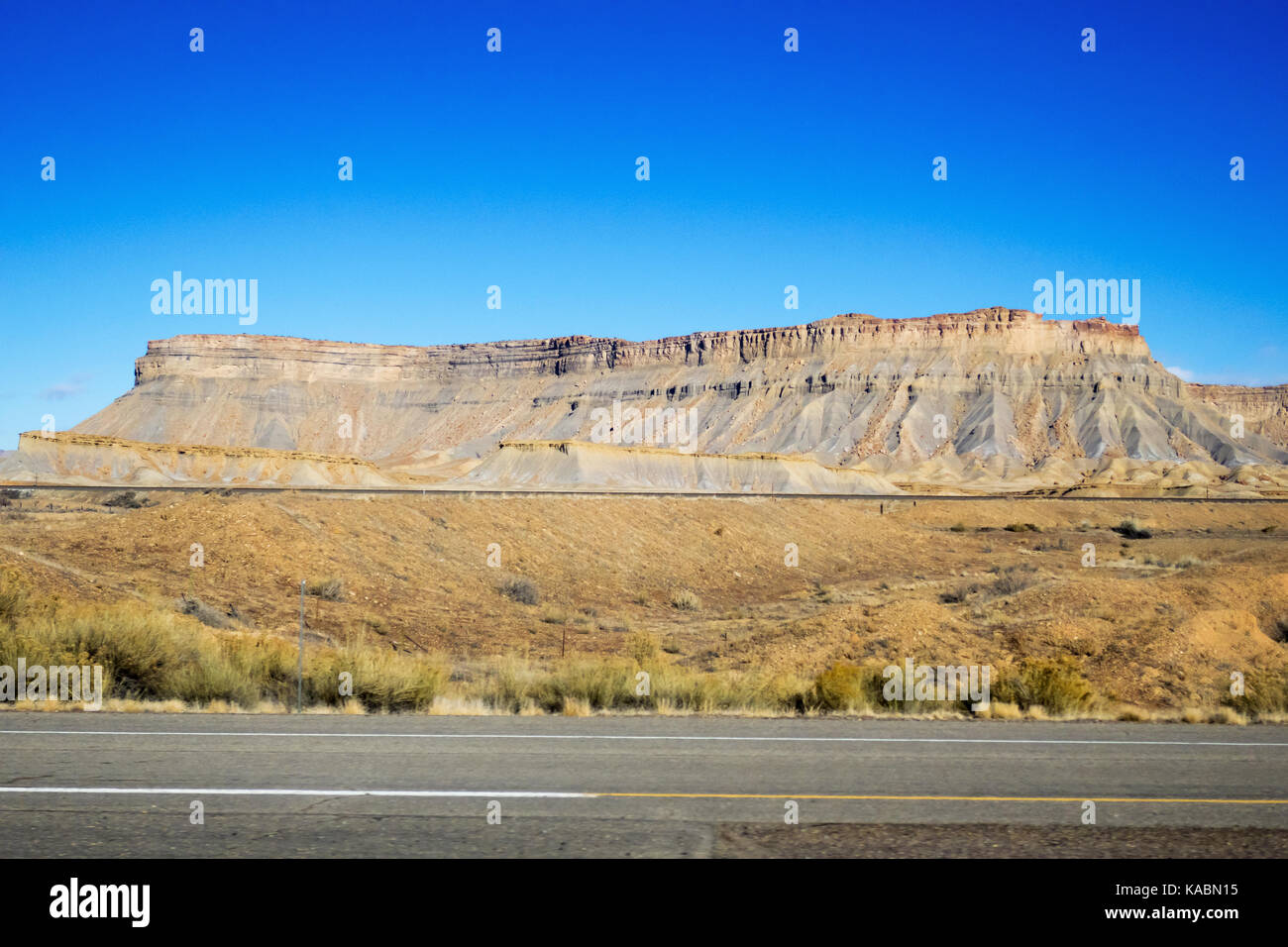 A rock plateau standing up on a blue sky with a road running past. Stock Photo