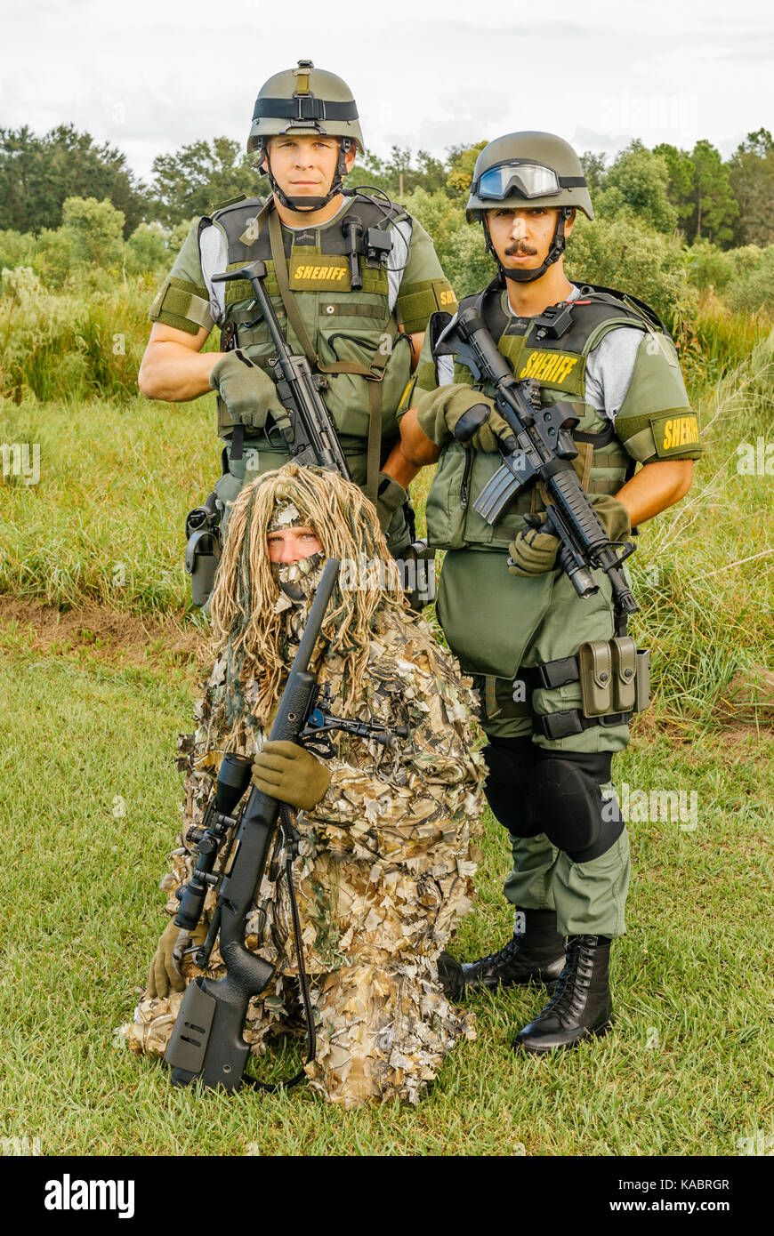 Three members of the Hillsborough County Sheriff's Office SWAT team, with full gear and one in a ghillie suit ready for a day of police training. Stock Photo
