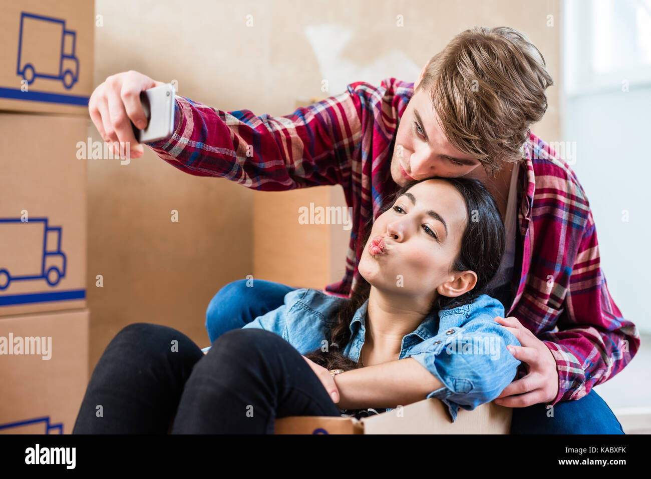 Young couple making a selfie to share the joy of moving in into  Stock Photo