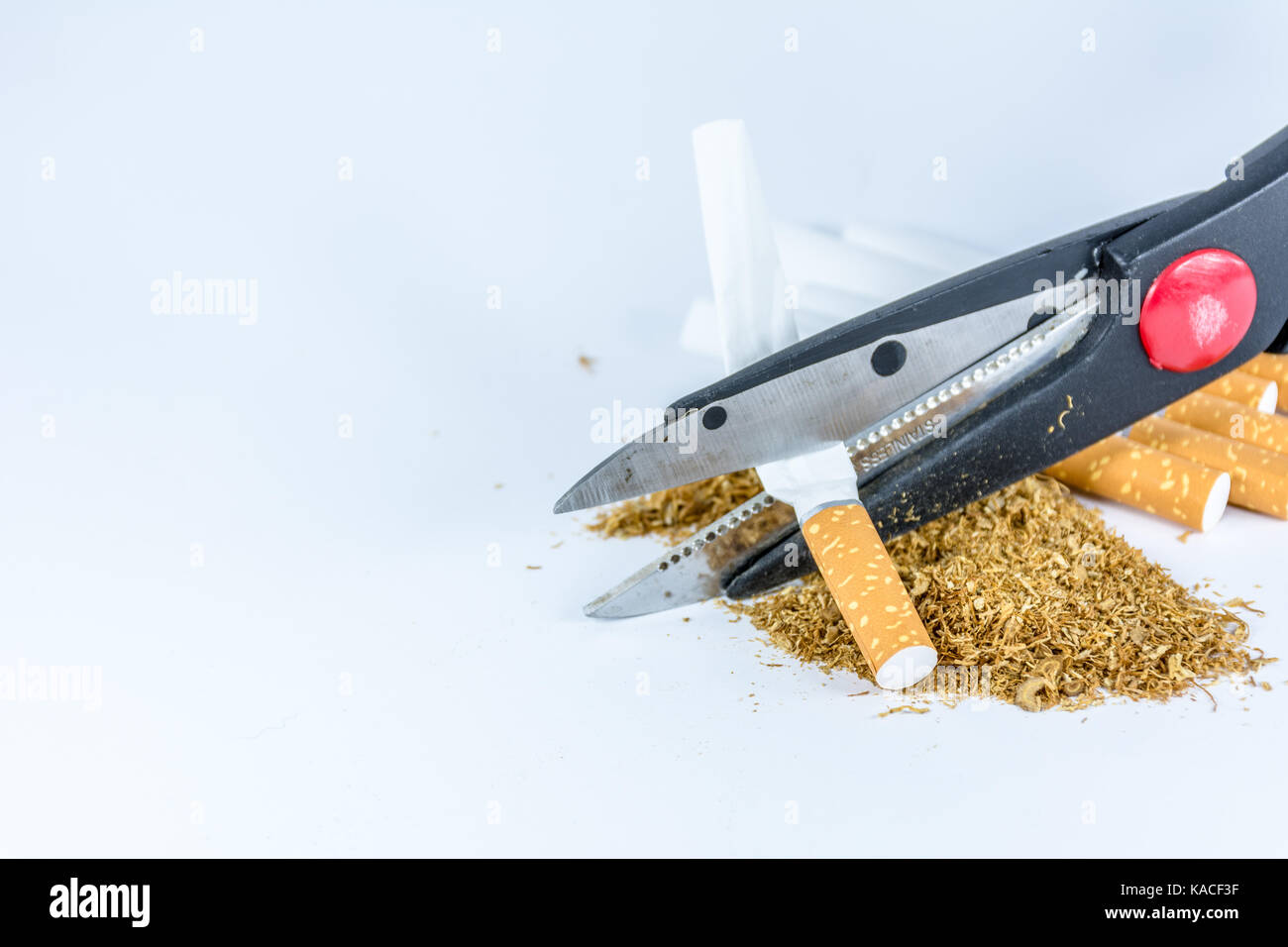 Empty cigarette tubes and tobacco with scissors on white background