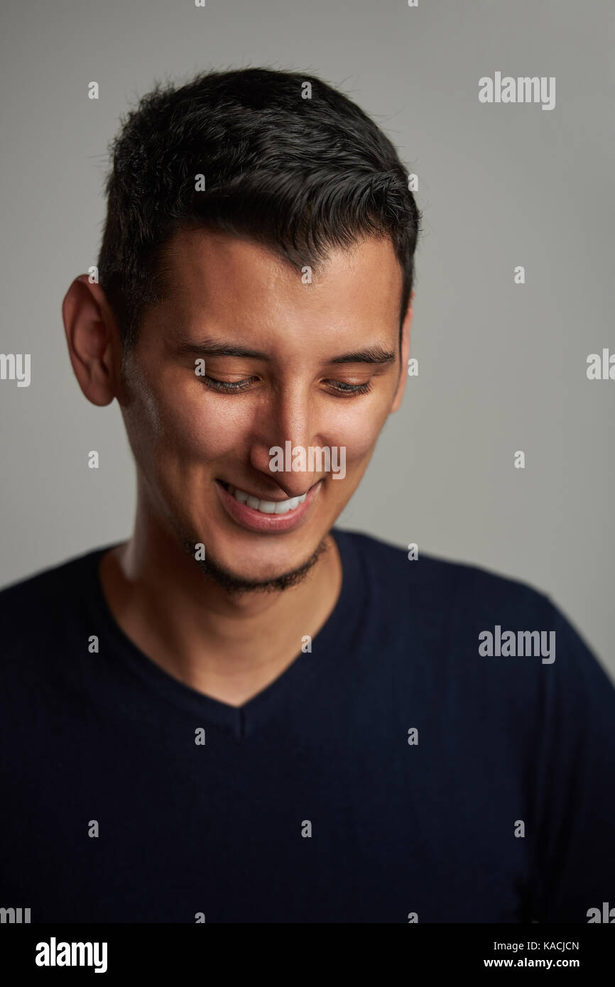 Happy shy young hispanic man smiling and look down Stock Photo
