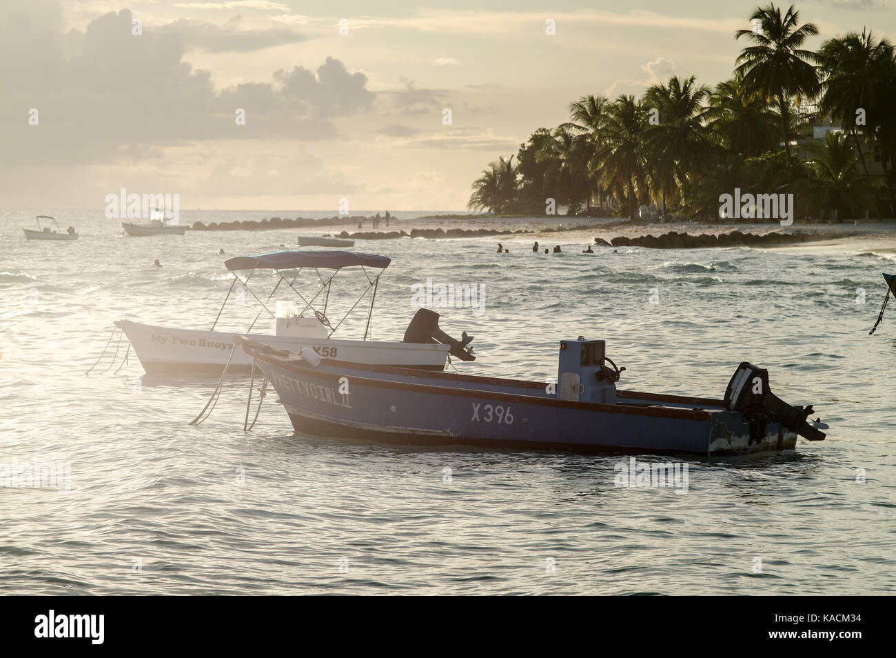Sun setting behind fishing boats moored in St. Laurence Gap on the west coast of Barbados Stock Photo