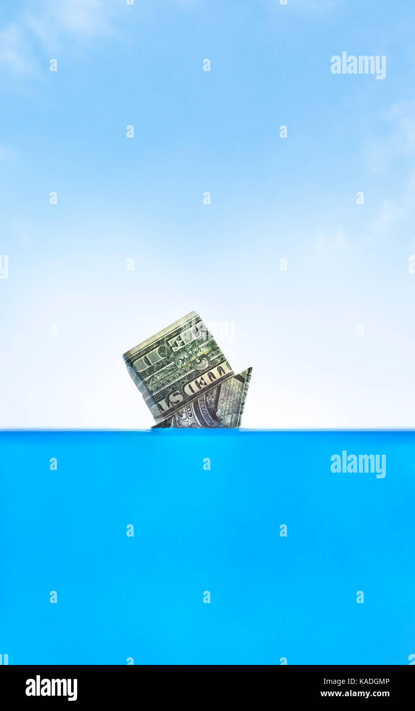Drowning in debt. Upside down origami cash home sinking in water. Stock Photo