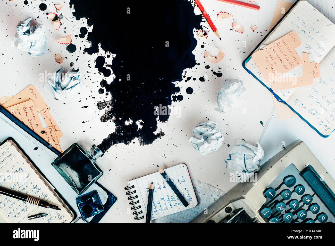 Writer workplace with spilled ink, stationery and a typewriter. Crumpled paper balls with pencils on a white wooden background, creative writing conce Stock Photo