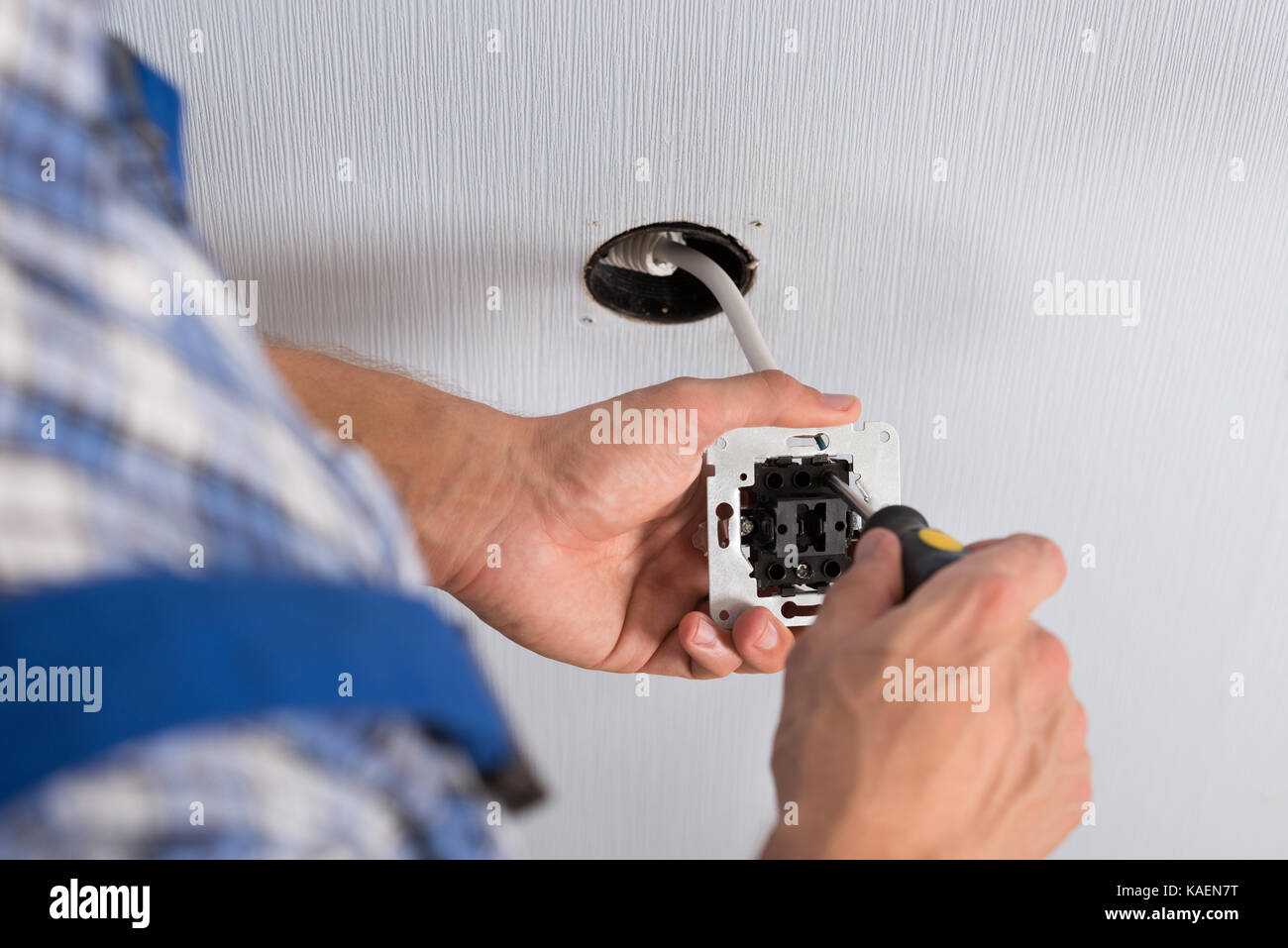 Close-up Of Electrician Hands With Screwdriver Installing Wall Socket Stock Photo