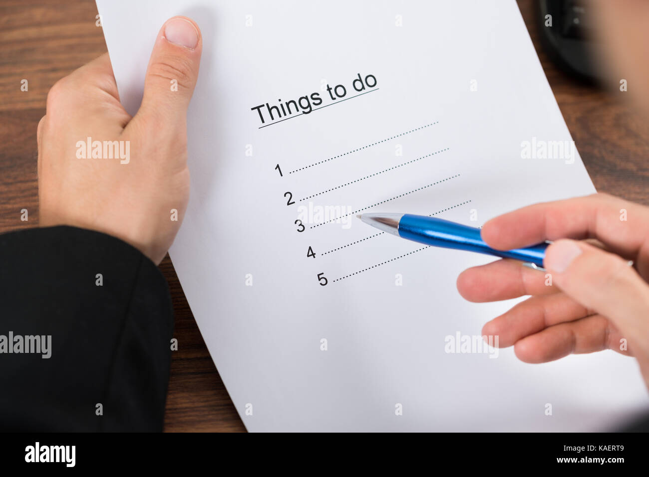 Close-up Of Businessman's Hand Holding To Do List And Pen Stock Photo