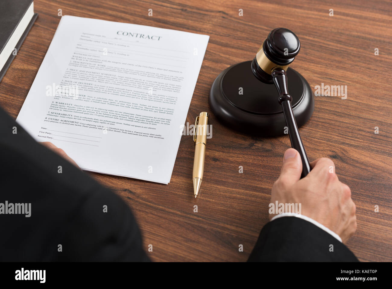 Close-up Of Judge Hitting The Gavel With Contract Paper At Desk Stock Photo