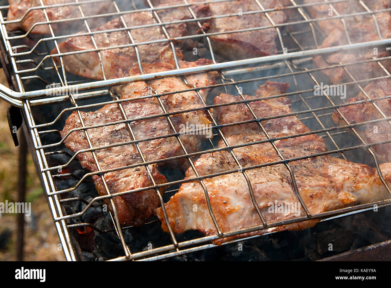 Juicy slices of meat cooking on an open flame grill. Roasted meat with