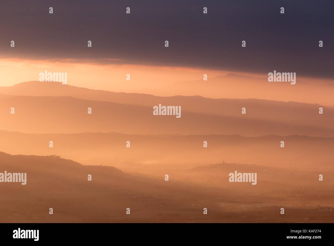 A valley filled by mist at sunset, with emerging hills and beautiful warm, orange tones Stock Photo