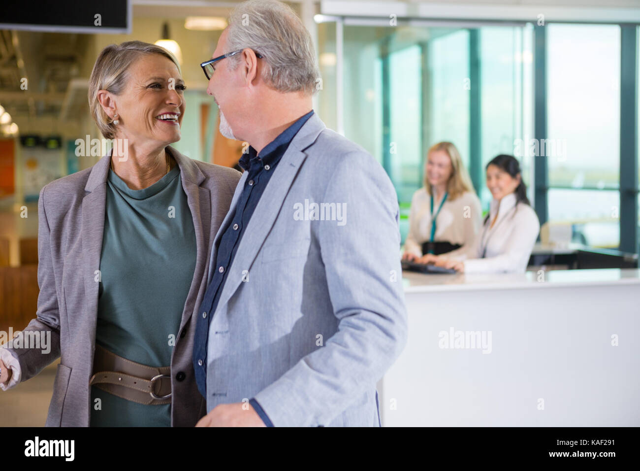 Smiling Business Couple Looking At Each Other In Airport Stock Photo