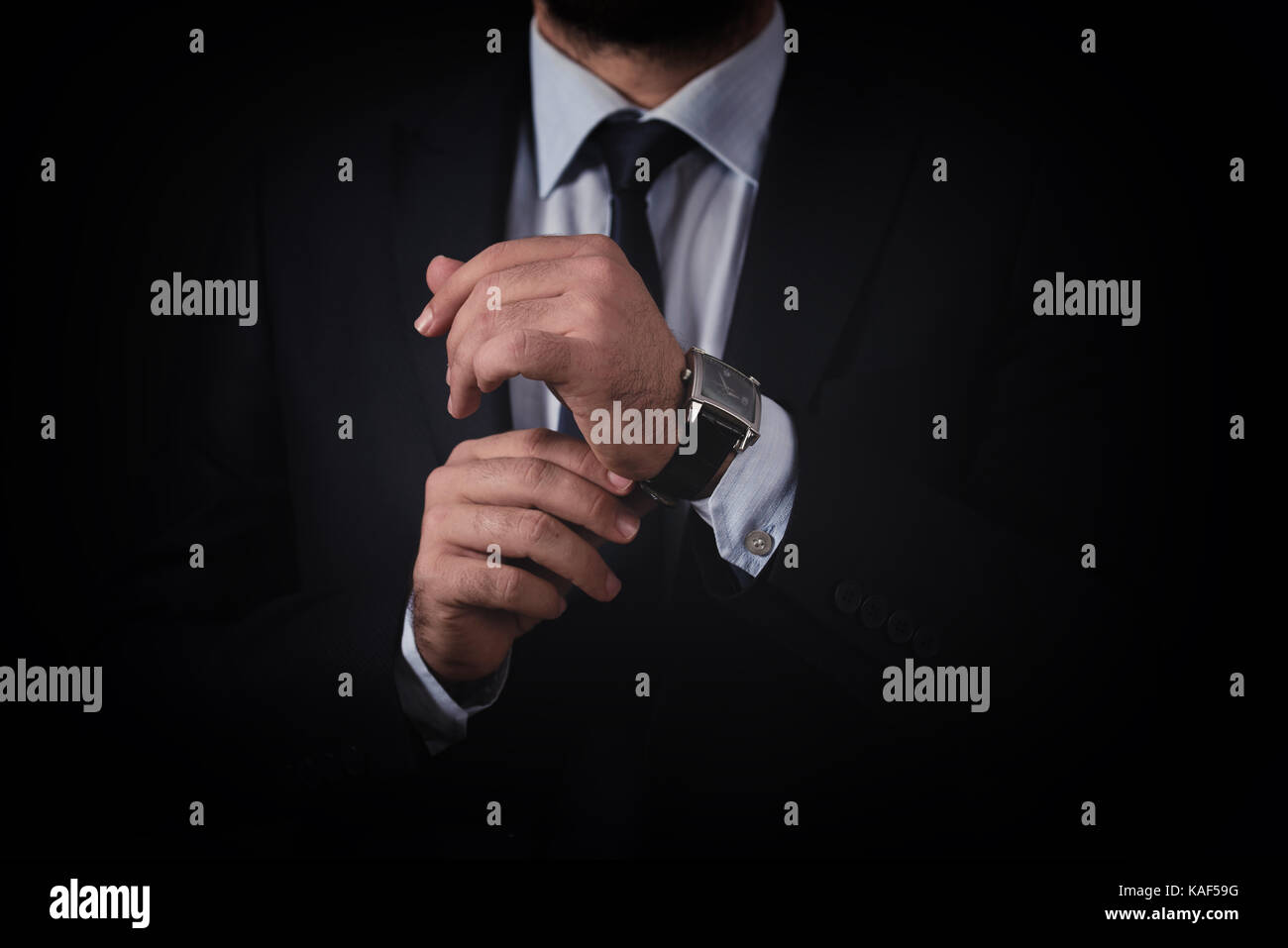 Businessman in black suit checking time from watch Stock Photo - Alamy