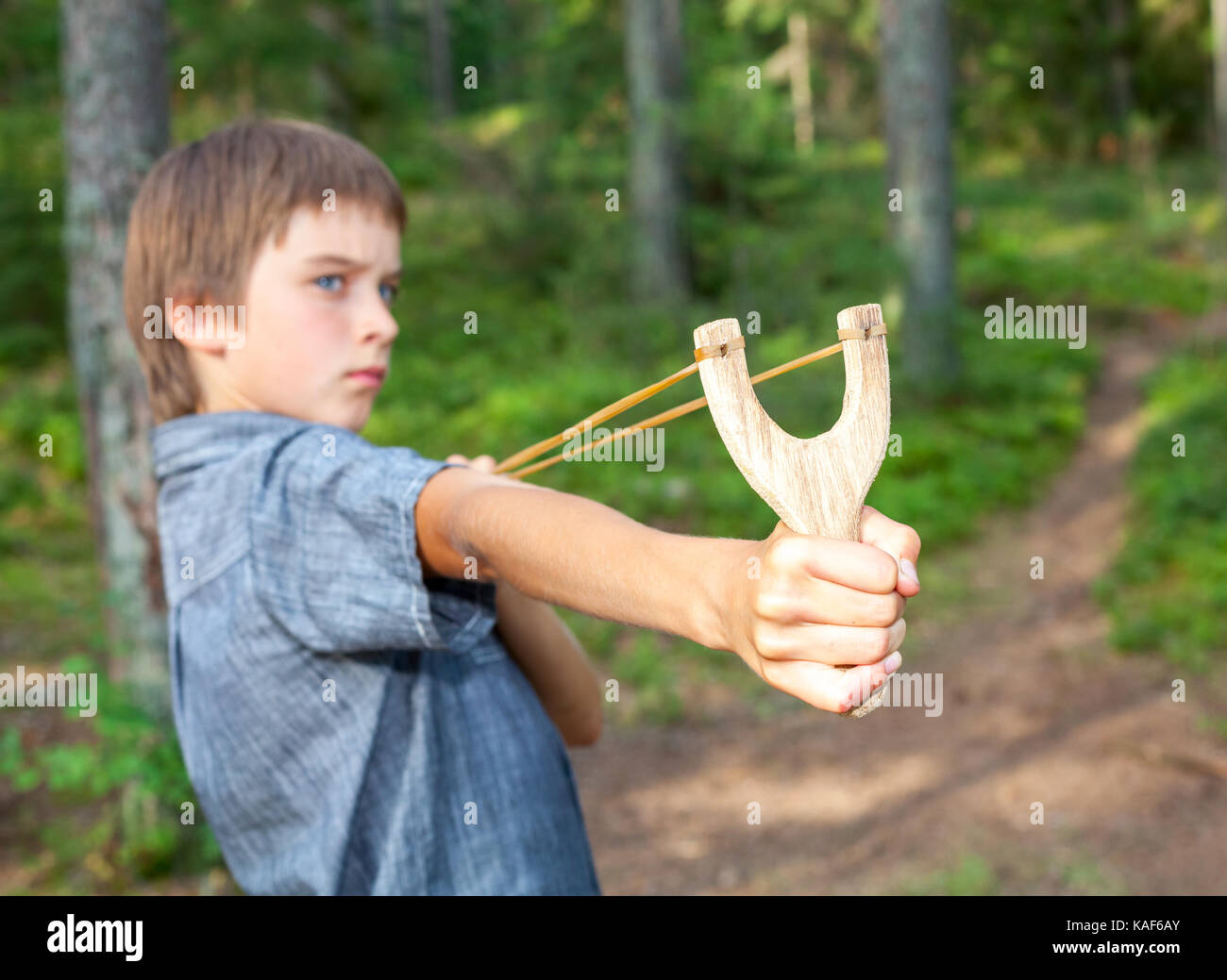 Boy aiming wooden slingshot outdoors Stock Photo