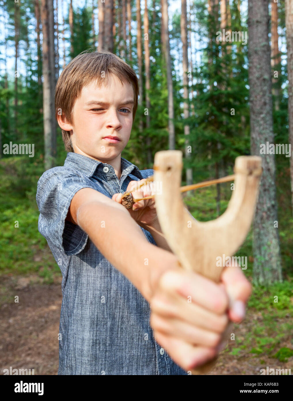 Boy aiming wooden slingshot outdoors Stock Photo